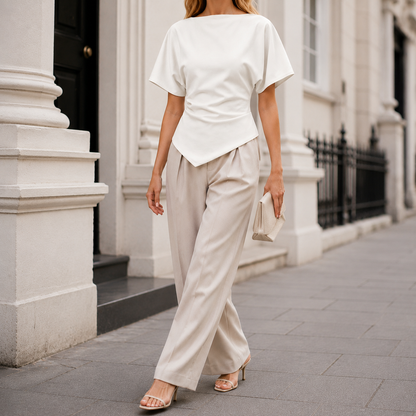 Structured blouse with bateau neckline, short draped sleeves, sculpted waist, and asymmetrical hem for a modern elegant silhouette