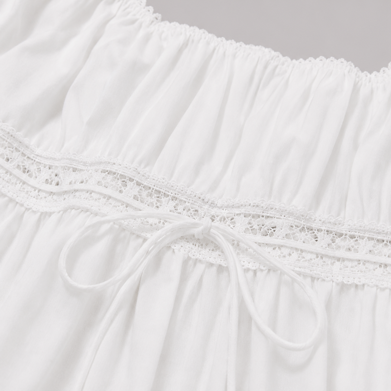 Square-neck peplum top with lace trim, short puff sleeves, adjustable drawstring waist, and flowy hem for a romantic feminine look
