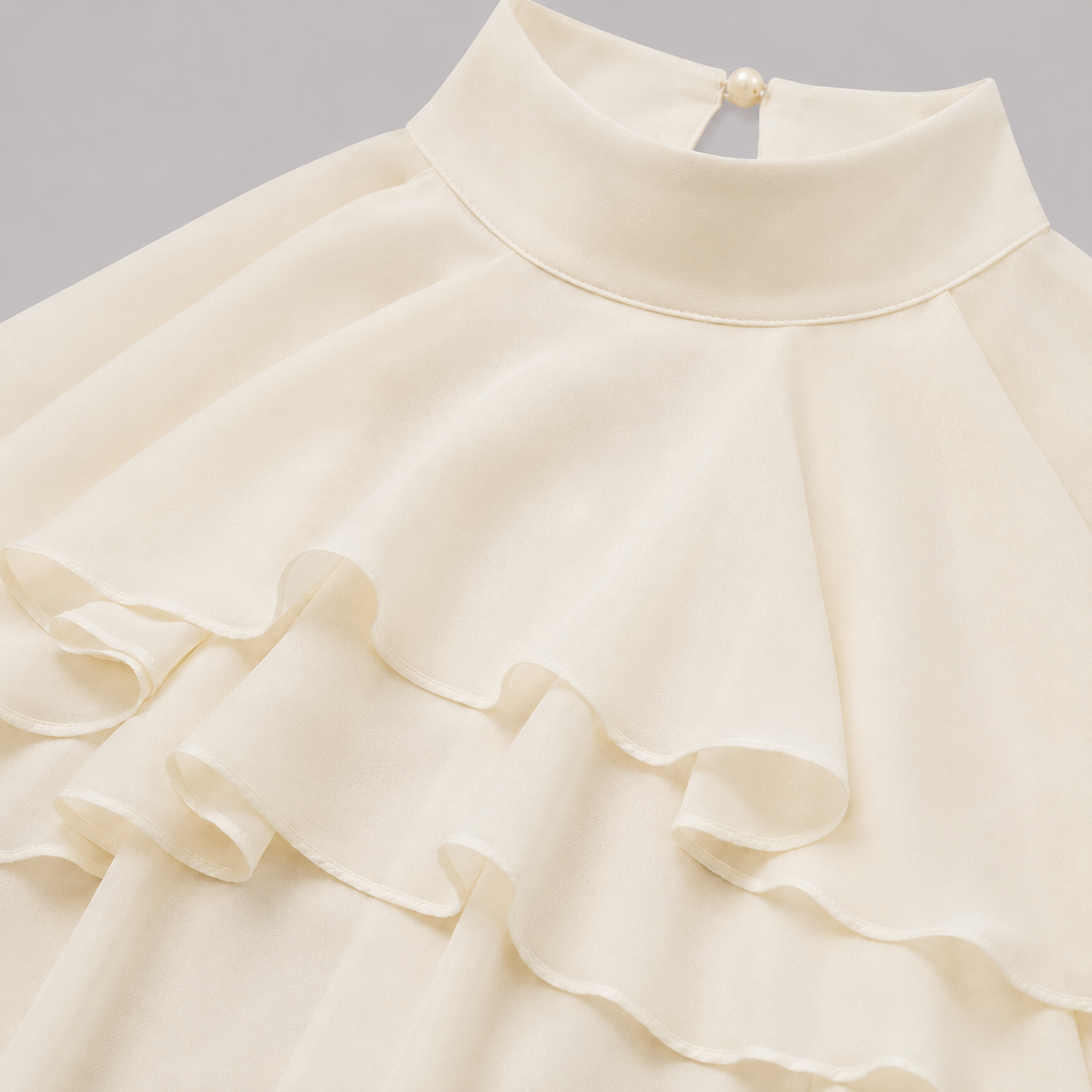 Sleeveless halter blouse with mock neckline, tiered cascading ruffles, and flowy chiffon silhouette for an elegant feminine look