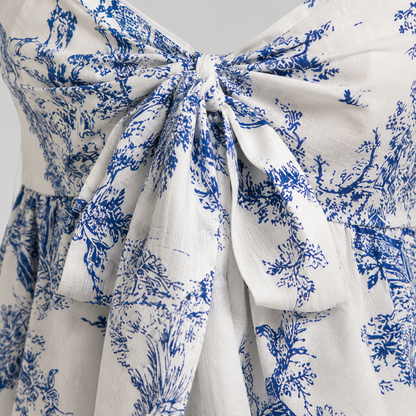 Sleeveless peplum cami top with sweetheart neckline, front bow tie detail, and flared hem in a toile-inspired print