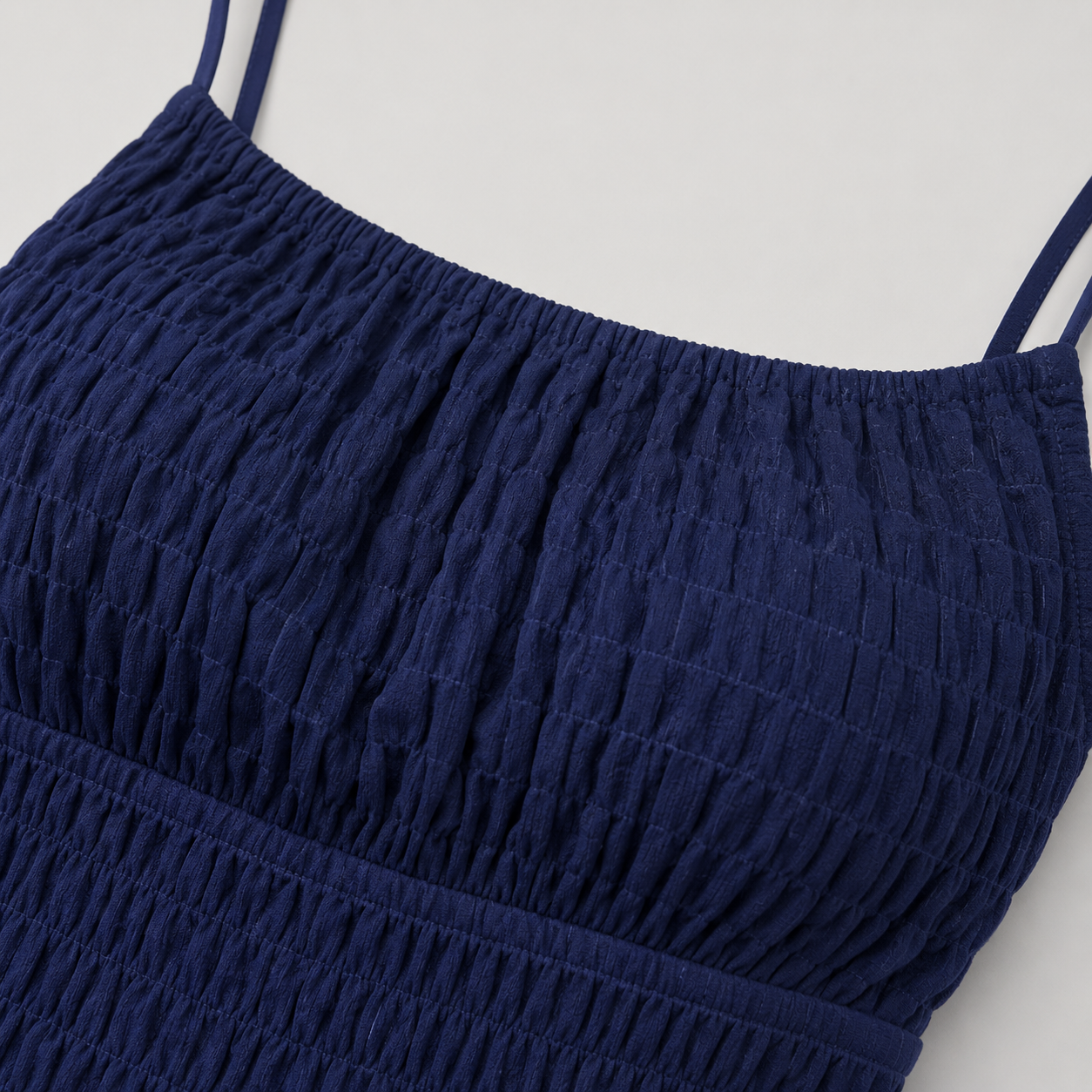 Sleeveless mini sundress with square neckline, smocked waistband, textured fabric, and flared ruffle hem