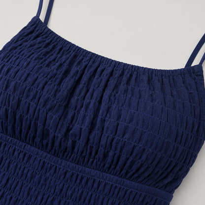 Sleeveless mini sundress with square neckline, smocked waistband, textured fabric, and flared ruffle hem